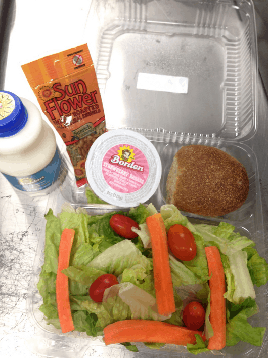 Fresh garden salad with romaine lettuce, carrots and tomato, served with a whole-grain roll, sunflower seeds, a low-fat yogurt and fat-free milk